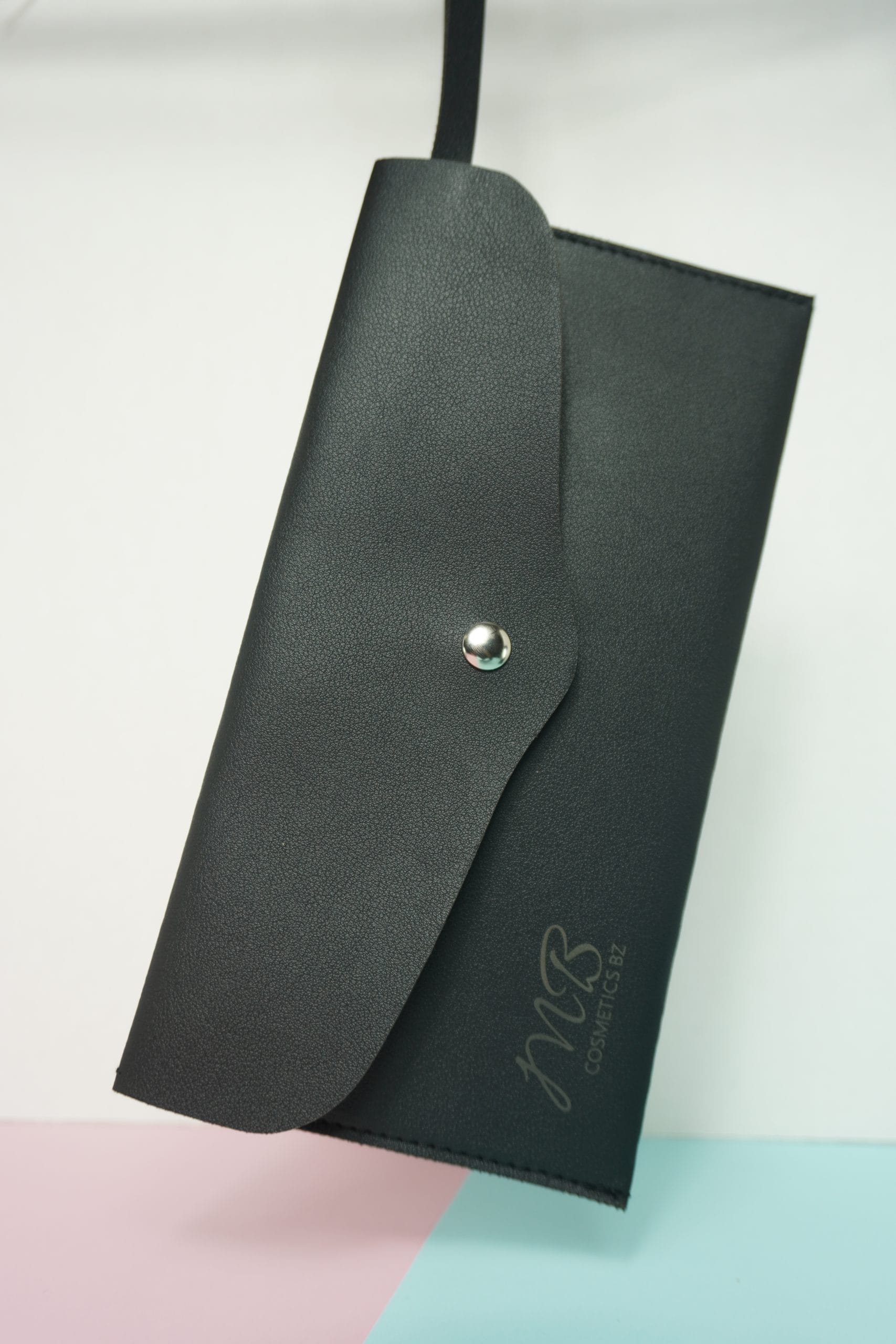 Sleek MB Cosmetics Brush Pouch Bag, a premium black case for travel featuring a silver button closure and the MB logo.